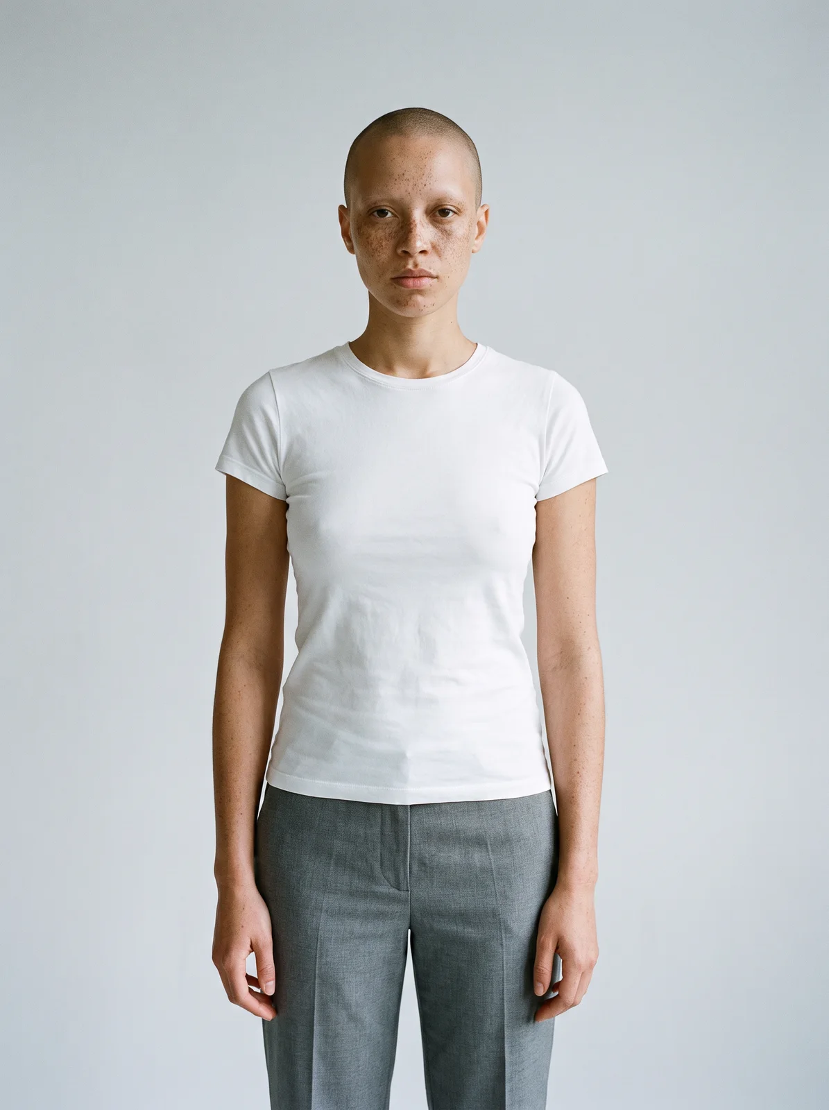 Photo de casting d'une mannequin élancée au crâne rasé et aux taches de rousseur, en t-shirt blanc