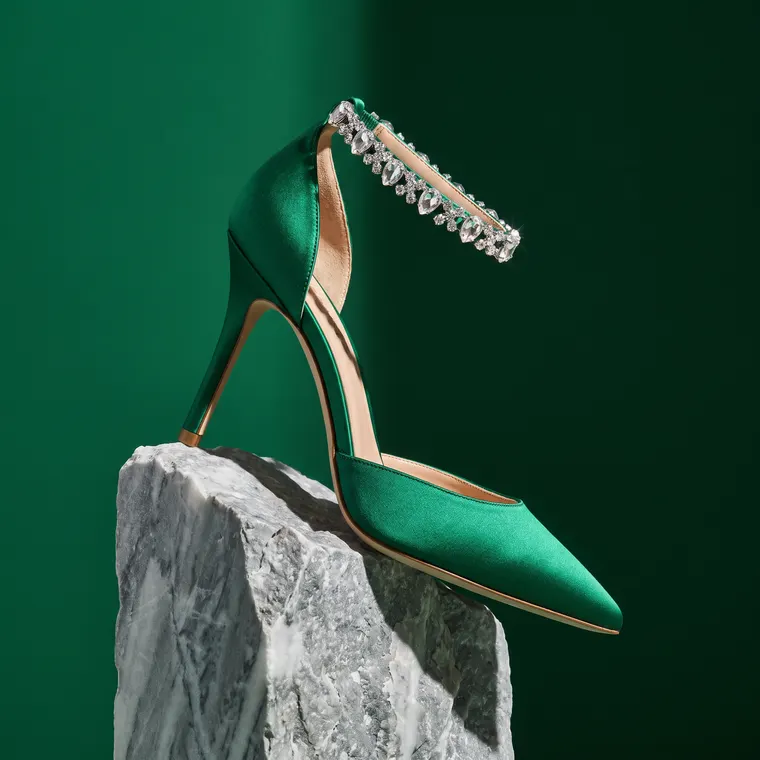 Escarpin à talon aiguille en satin vert émeraude, bride de cheville en cristaux, sur un bloc de marbre brut